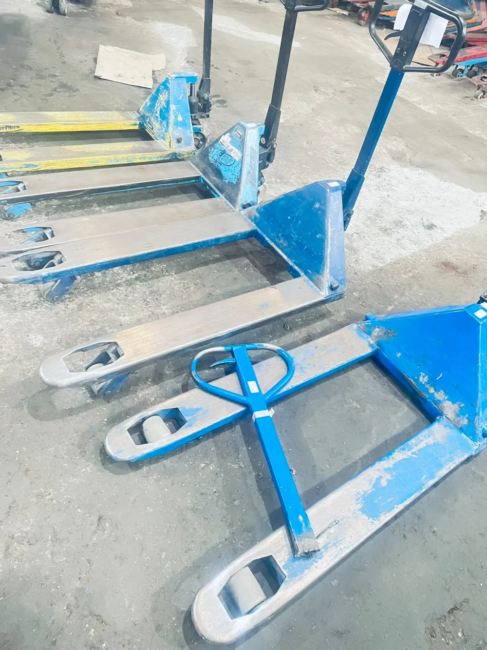 Paleteiras hidráulicas azuis aguardando avaliação na oficina da TECNOHIDRO